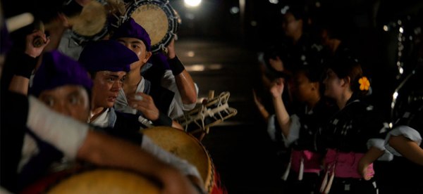 Young men and women drum and dance Eisa at night on the street
